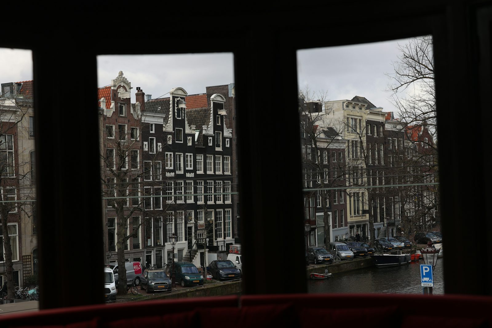 Canal houses seen through the windows of an apartment across the water
